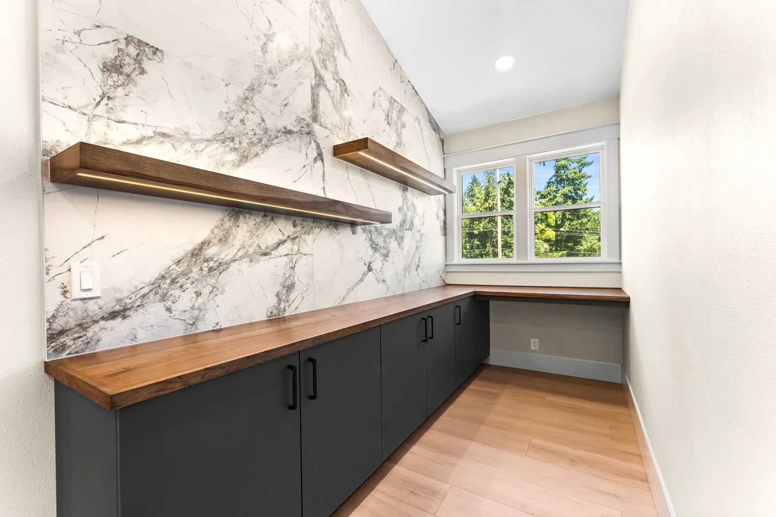 Custom pantry with marble backsplash, floating shelves, and integrated wiring