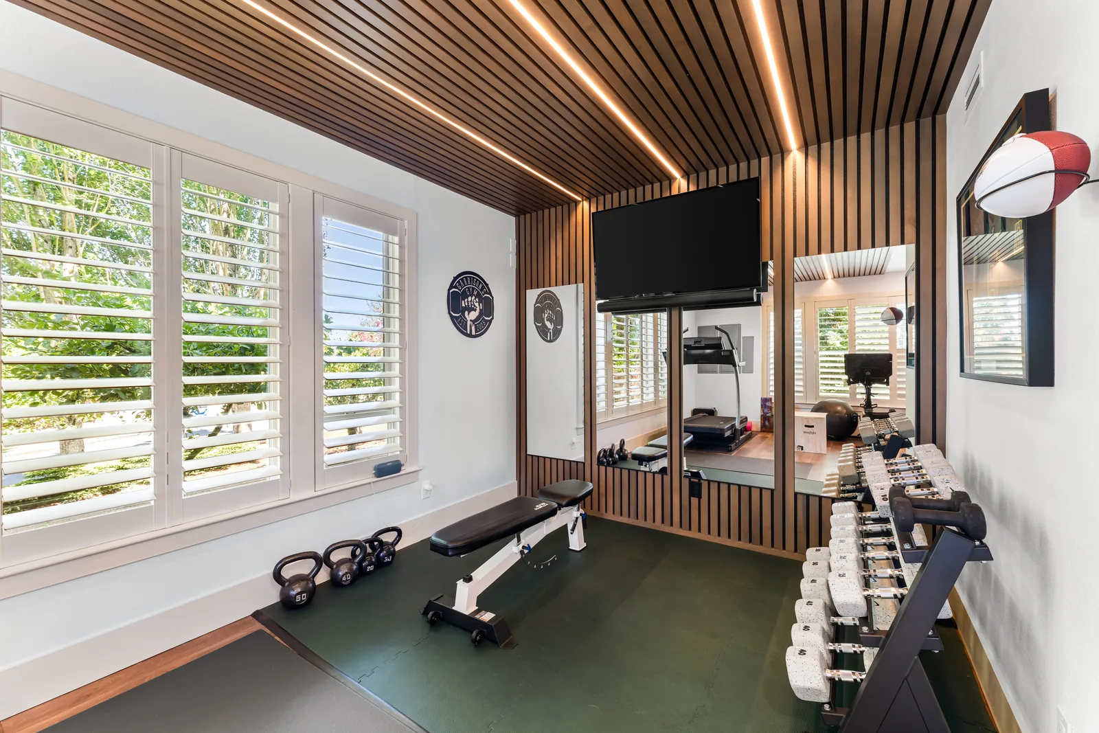 Custom home gym with wood-slat ceiling and LED accent-lighting installation