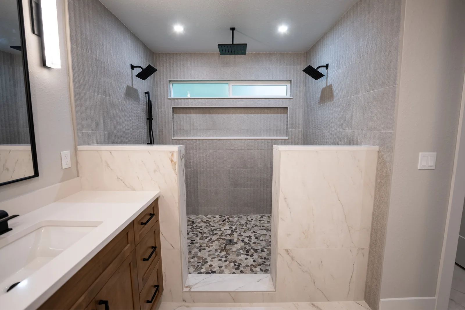 Custom shower with dual rain heads and overhead lighting installation